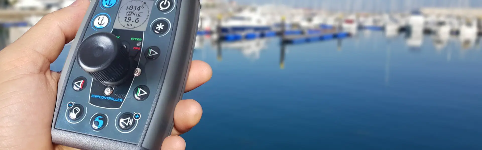 Shipcontroller EZVector remote held in hand above a calm marina